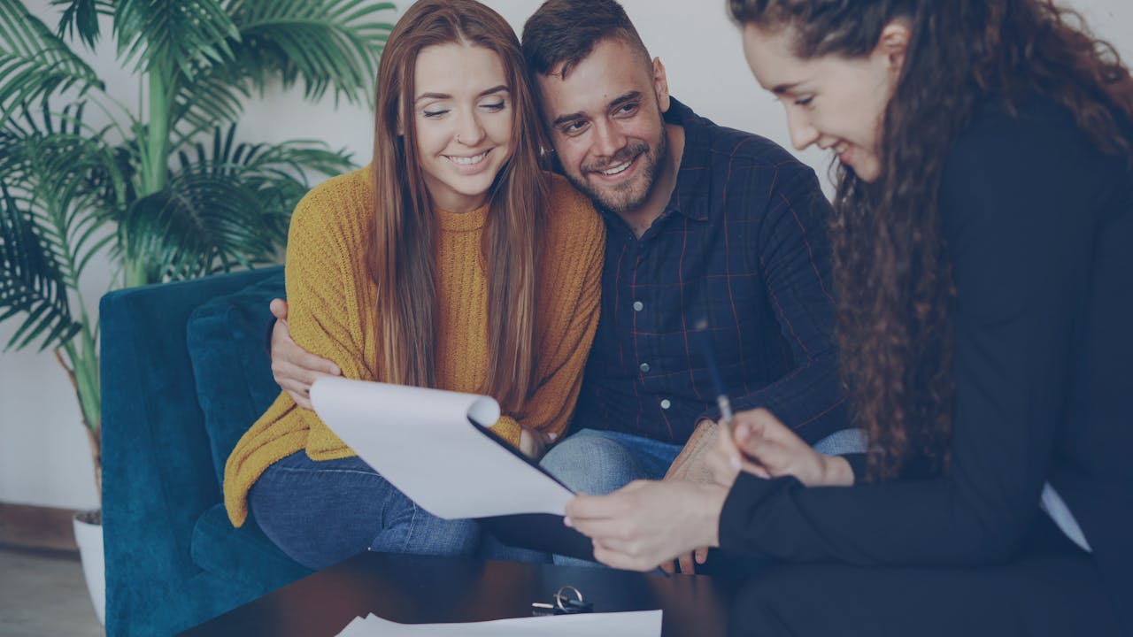 Happy couple discussing finance with advisor in cozy office setting.